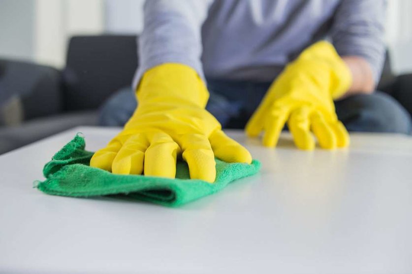 people, housework and housekeeping concept - close up of man hands cleaning table with cloth at home