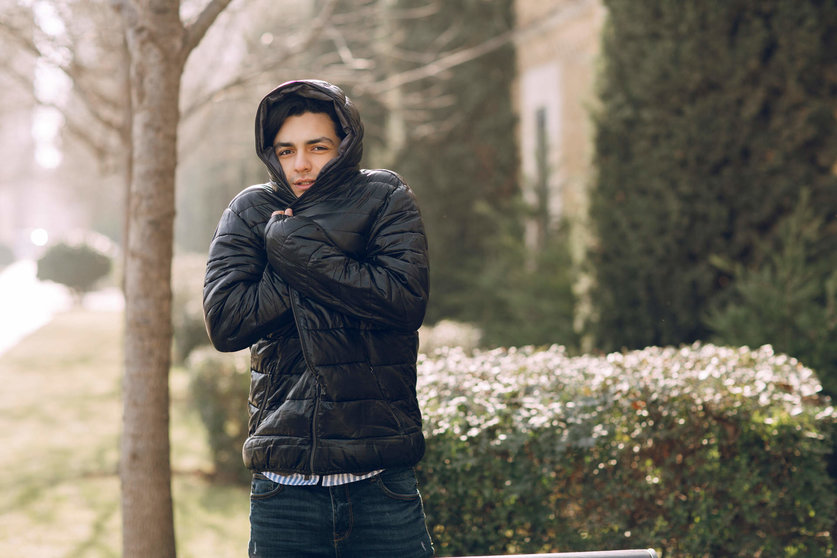 Man feeling cold in the black winter jacket in the park. High quality photo