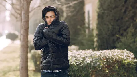 Man feeling cold in the black winter jacket in the park. High quality photo